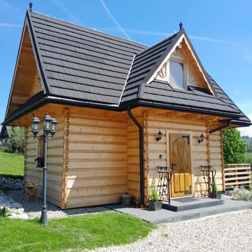 a small wooden cabin with a black roof at Domek u Śpiewoka 1 in Maruszyna
