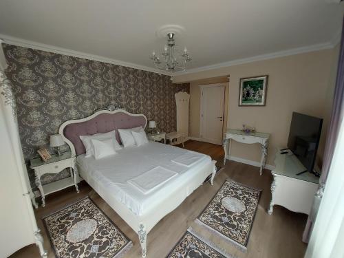 a bedroom with a white bed and a tv at Conacul Poetilor in Gura Rîului
