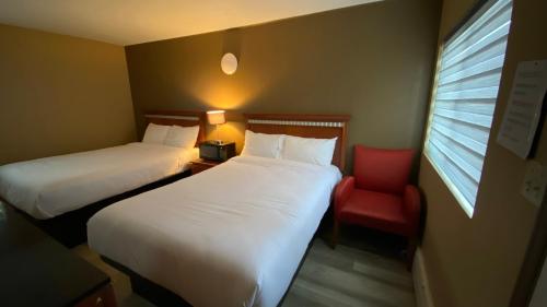 Una habitación de hotel con dos camas y una silla roja. en Rolphton Motel and Restaurant, en Moor Lake Station