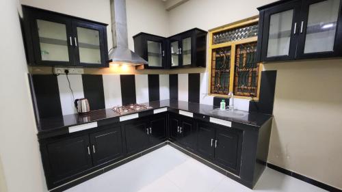 una cocina con armarios negros y fregadero en Calm Guest, en Trincomalee