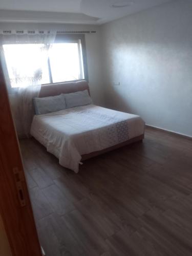 a bedroom with a large bed with a window at Villa en location in El Jadida