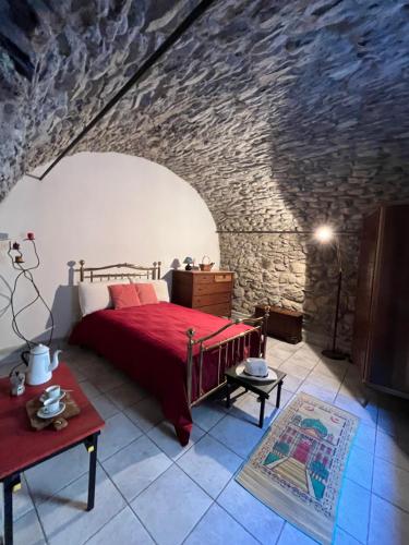 a bedroom with a bed and a stone wall at Casa Victoria - Full equipped stone house in Rocchetta Nervina