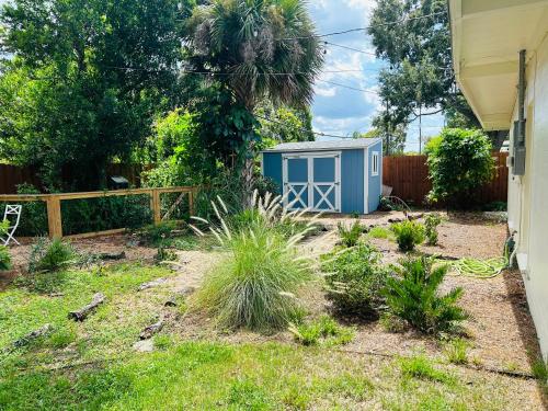 einen Garten mit einem blauen Schuppen neben einem Zaun in der Unterkunft GardenHouse @AudubonPark Sleeps 8 in Orlando