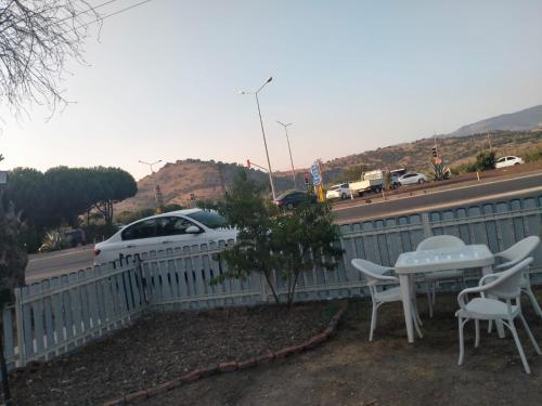uma cerca branca com uma mesa e cadeiras e um carro em İN HOUSE BUNGLOW em Dikili