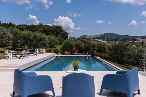a swimming pool with blue chairs and a table at Appartamento La Mignola in Campiglia Marittima