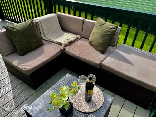 a couch on a deck with a table and a bottle of beer at The Ascot by North Shacks in Slaley