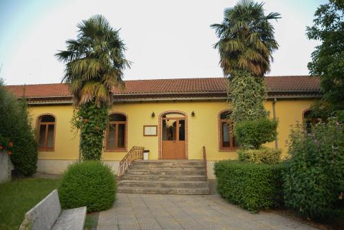 a yellow house with two palm trees and stairs at Village of Peace - House 40 in Shkodër