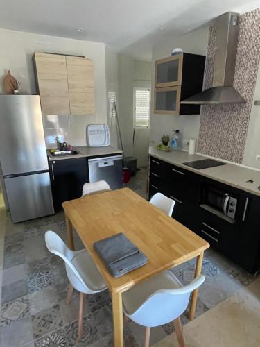 a kitchen with a wooden table and white chairs at Vistas al mar a 10 metros de la Playa de Regla PARKING GRATIS in Chipiona