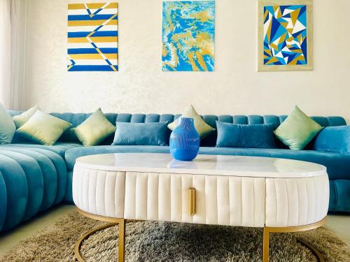 a living room with a blue couch and a white coffee table at Appartement Cozy avec piscine in Sidi Rahal
