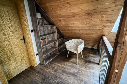 a stairway with a chair and a book shelf at Hamerská chaloupka in Hlinsko