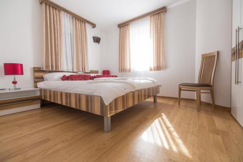 a bedroom with a bed and a chair and windows at Apartments Villa Novak 1 in Okrug Donji