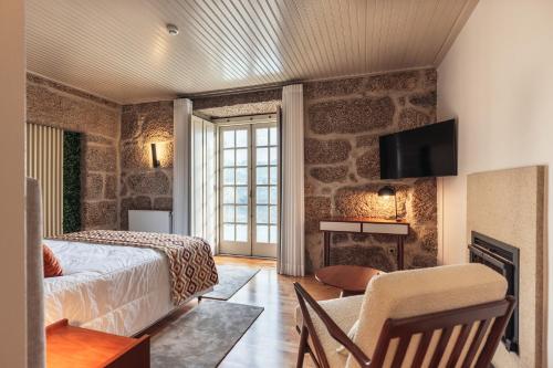 a bedroom with a bed and a tv on a wall at Casa da Ribeira in Marco de Canavezes