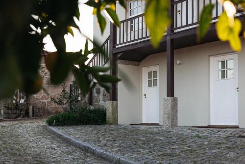 a house with white doors and a cobblestone driveway at Casa da Ribeira in Marco de Canavezes