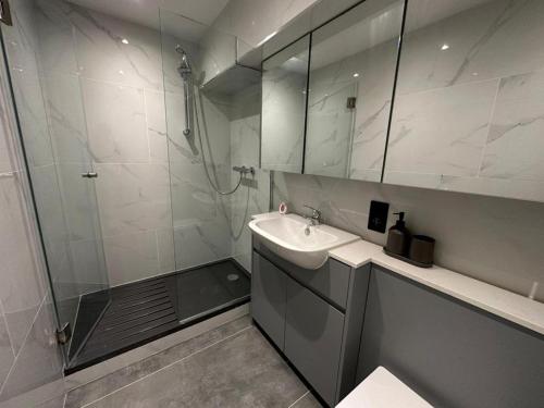 Two Bedroom House In Kilburn في لندن: حمام مع دش ومغسلة ومرآة