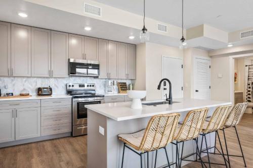 een keuken met witte kasten en een keukeneiland met barkrukken bij Coco Dunes condo in St. George