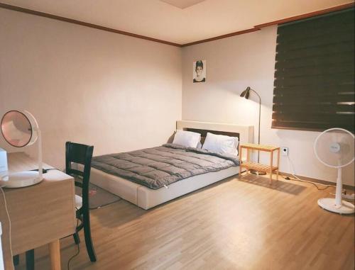 ein Schlafzimmer mit einem Bett und einem Schreibtisch mit einer Lampe in der Unterkunft Peace and Quiet in Seoul