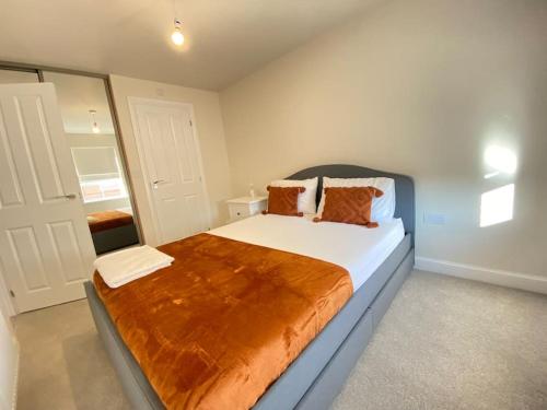 a bedroom with a large bed with orange pillows at Brand New Stylish 3 Bed House in Milton Keynes