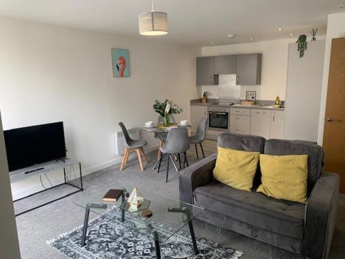 a living room with a couch and a table and a kitchen at Beautiful Manchester 2 bedroom apartment in Manchester