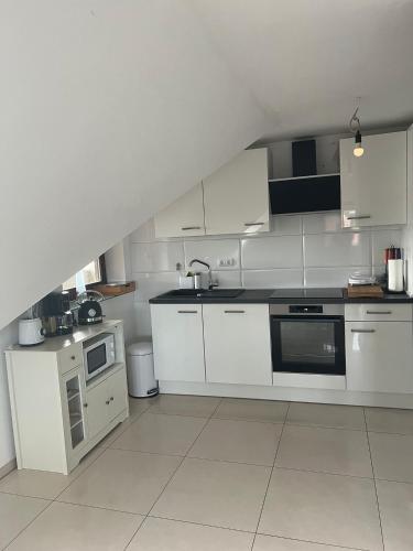 a white kitchen with white cabinets and appliances at FMA Ferienwohnung Alfdorf in Alfdorf