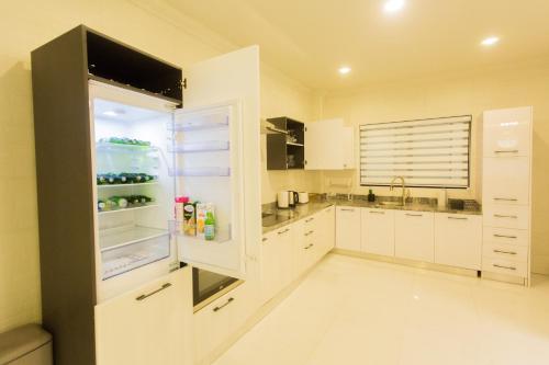 een keuken met witte kasten en een koelkast bij Kumasi Luxury Apartments @ The Fairview in Kumasi