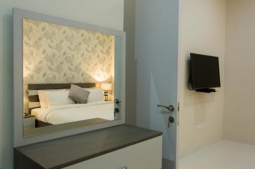 a bedroom with a mirror with a bed and a tv at Kumasi Luxury Apartments @ The Fairview in Kumasi