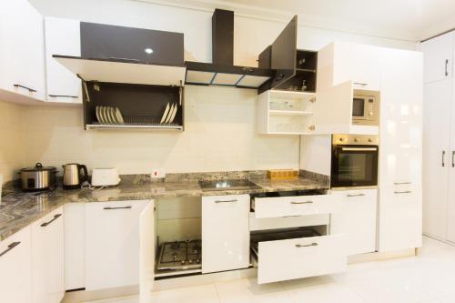 a kitchen with white cabinets and black appliances at Kumasi Luxury Apartments @ The Fairview in Kumasi