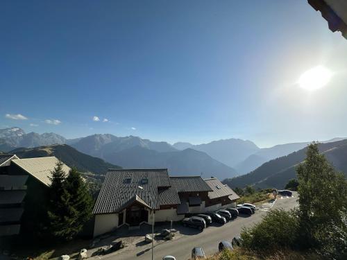 un bâtiment avec des voitures garées dans un parking avec des montagnes dans l'établissement Sunny studio Mountain View balcony Alpe d Huez Studio ensoleillé balcon vue montagne, à L'Alpe-d'Huez