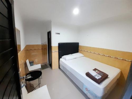 a small room with a bed and a chair in it at Hotel Srikandi Baru in Yogyakarta