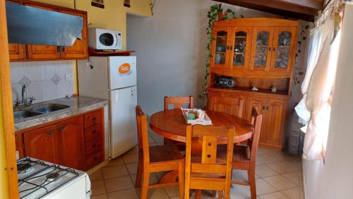 a kitchen with a table and chairs and a white refrigerator at CASA los ciruelos in El Bolsón