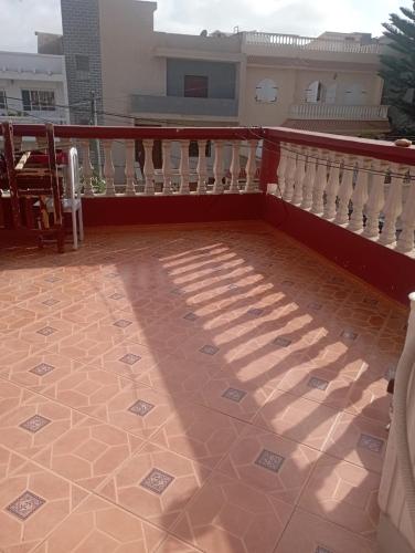 een balkon met een witte leuning en een tegelvloer bij Sablettes in Oulad Akkou