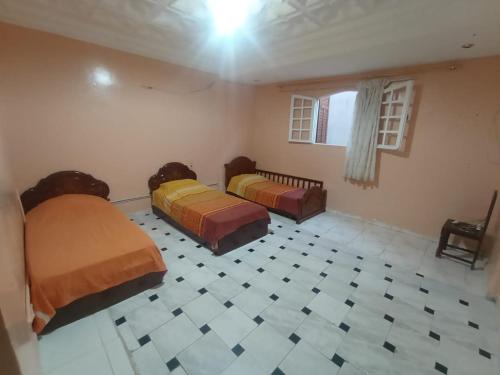 1 dormitorio con 2 camas y suelo de baldosa en Sablettes, en Oulad Akkou
