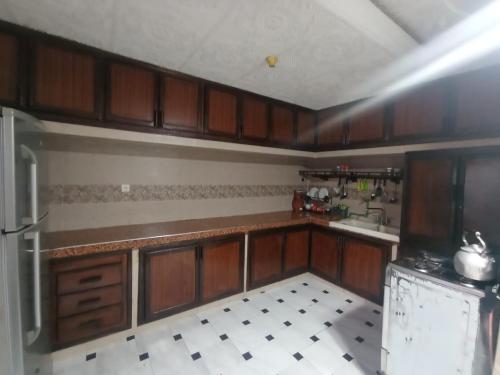a kitchen with wooden cabinets and a tile floor at Sablettes in Oulad Akkou