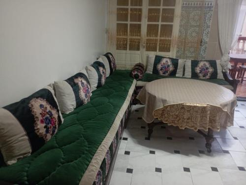 een woonkamer met een groene bank en een tafel bij Sablettes in Oulad Akkou