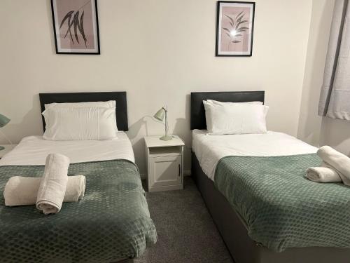a bedroom with two beds with towels on them at Spacious Comfortable 4 bedroom house in Aylesbury