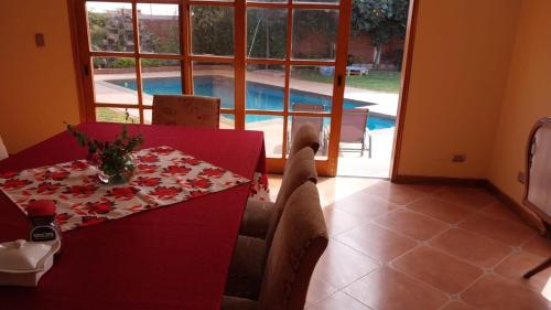 a dining room with a red table and a pool at Las buganvilias in Pachacamac