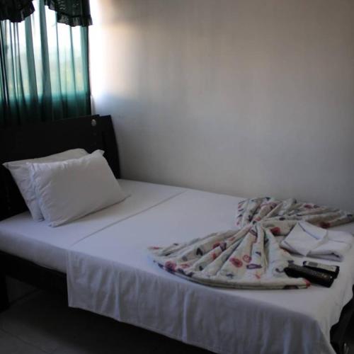 Hotel Villa Rocio Curumani في Curumaní: سرير ابيض وعليه بطانيه والريموت كنترول