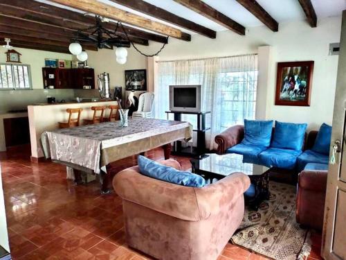 uma sala de estar com uma mesa e sofás azuis em Villa Natalia Finca Ecologica em Papagalleros