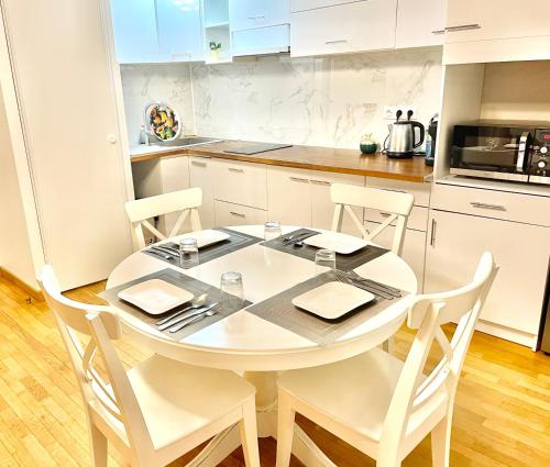 a white kitchen with a white table and chairs at Un grand deux pièces in Charenton-le-Pont