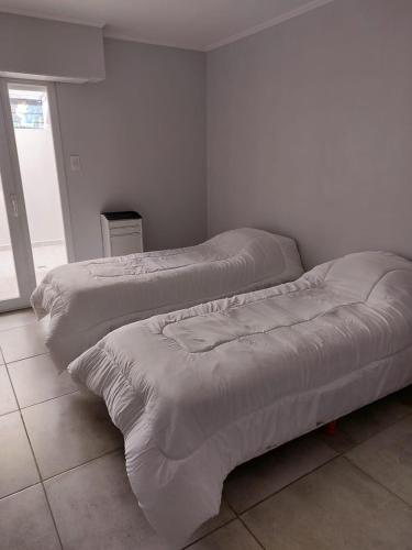 Duas camas num quarto com paredes brancas em Departamento de Caro em Tandil