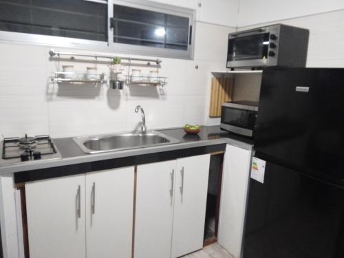 eine Küche mit einer Spüle und einem schwarzen Kühlschrank in der Unterkunft Tu lugar de relax! Se reserva solo con seña in Guazú-Virá