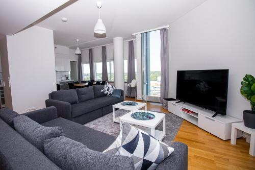 ein Wohnzimmer mit Sofas und einem großen TV in der Unterkunft Flexi Homes Itäkeskus in Helsinki