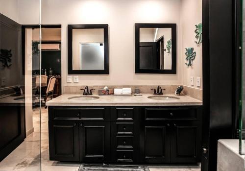 a bathroom with two sinks and two mirrors at Stunning 3BR Condo with Ocean Views, Golf Course & Resort Amenities in Cabo San Lucas
