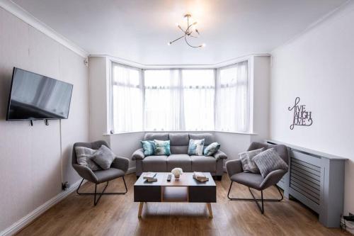 uma sala de estar com um sofá e duas cadeiras e uma televisão em Windsor House 3 Bedrooms Sleeps 8 em Manchester