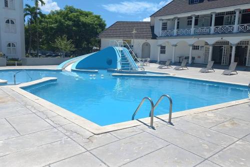 a swimming pool with a blue slide in front of a building at Modern Penthouse @ Sandcastles in Ocho Rios