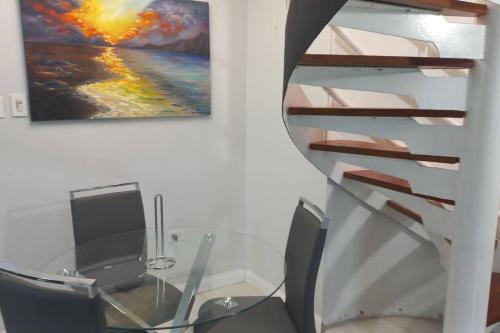 a glass table and a staircase in a room with a painting at Modern Penthouse @ Sandcastles in Ocho Rios