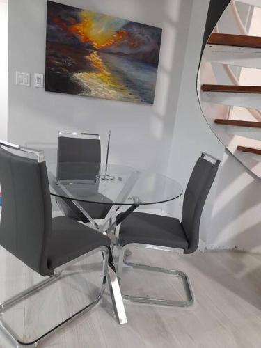 a glass table and chairs in a room with a painting at Modern Penthouse @ Sandcastles in Ocho Rios