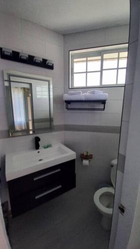 a bathroom with a sink and a toilet and a mirror at Modern Penthouse @ Sandcastles in Ocho Rios