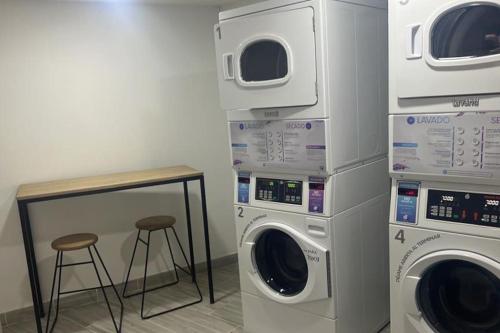 eine Waschküche mit drei Waschmaschinen und einem Stuhl in der Unterkunft Urban Manizales in Manizales