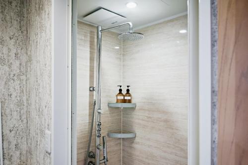 baño con ducha y puerta de cristal en Hostel Casa Noda, en Nagasaki