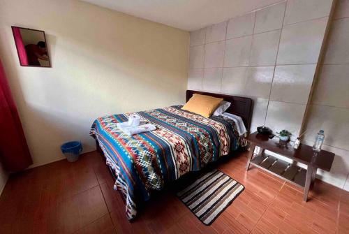a small bedroom with a bed and a table at Hermosa habitación con terraza y vista al pastaza in Baños